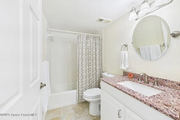 a bathroom with a granite countertop toilet a sink and a mirror