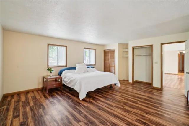 a view of an empty room with wooden floor fireplace and a window