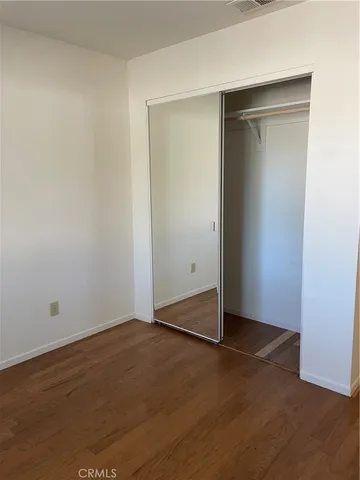 an empty room with wooden floor and closet