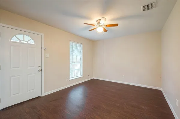 an empty room with wooden floor fan and windows