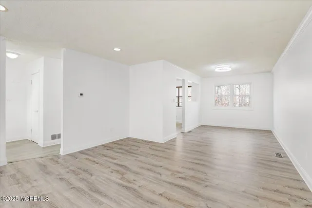 a view of an empty room with window and wooden floor
