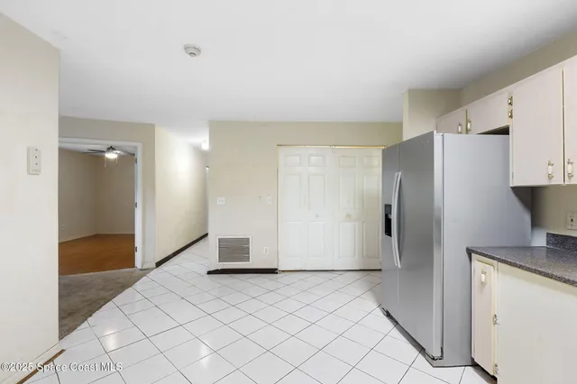 a view of a refrigerator in kitchen and white cabinets