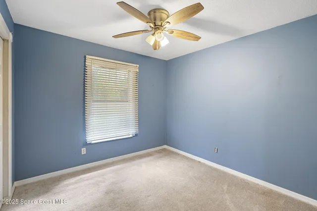 an empty room with windows and chandelier fan