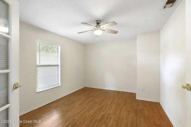 a view of empty room with wooden floor and fan