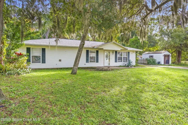 a front view of a house with a yard and trees