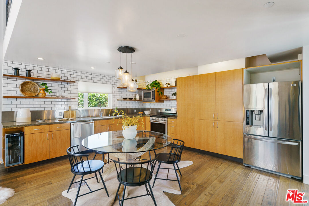 1228 21st Street, Unit D Santa Monica, CA 90404 - Photo 4 of 32 a kitchen with stainless steel appliances granite countertop a dining table chairs refrigerator and sink