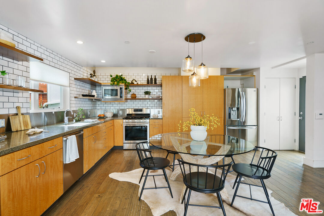 1228 21st Street, Unit D Santa Monica, CA 90404 - Photo 5 of 32 a kitchen with stainless steel appliances granite countertop a table chairs and a refrigerator
