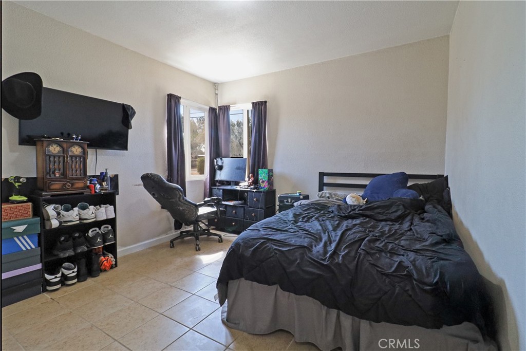 25466 Jasper Road Barstow, CA 92311 - Photo 24 of 32 a bedroom with a bed a large mirror and a desk
