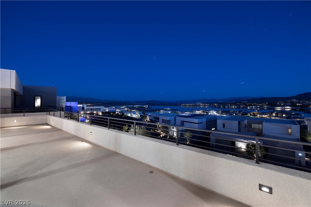 25 Falling Ridge Lane Henderson, NV 89011 - Photo 25 of 48 Perched atop a modern structure, this terrace offers breathtaking panoramic city lights and lake views under a twilight sky.