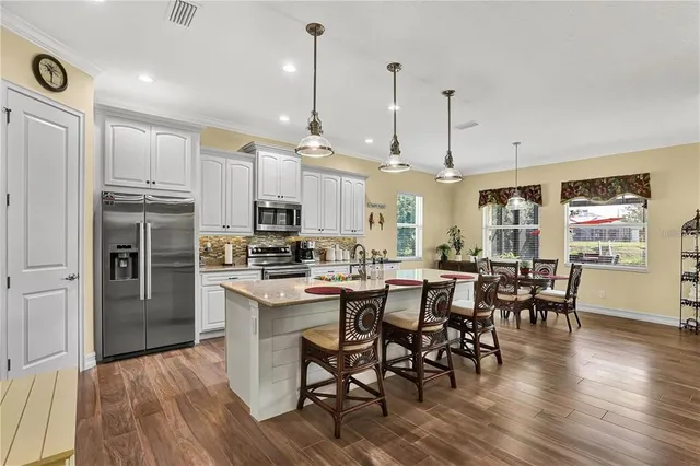 a large kitchen with cabinets chairs and wooden floor