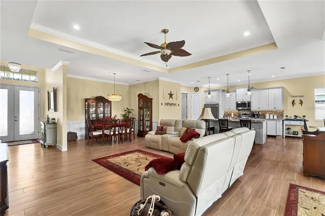 a living room with furniture kitchen view and a wooden floor