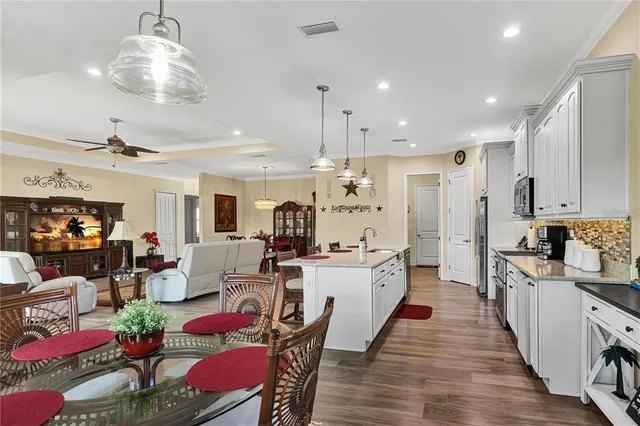 a large kitchen with sink a refrigerator and chairs