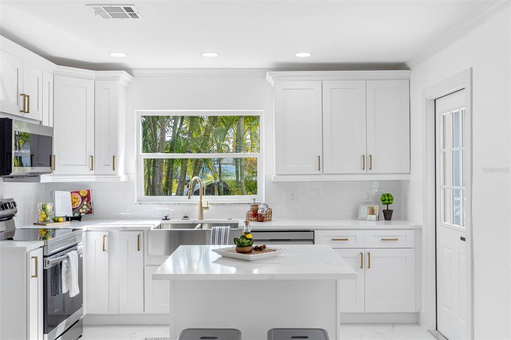 785 115th Avenue Treasure Island, FL 33706 - Photo 17 of 46 a kitchen with stainless steel appliances a sink a stove a refrigerator cabinets and a window
