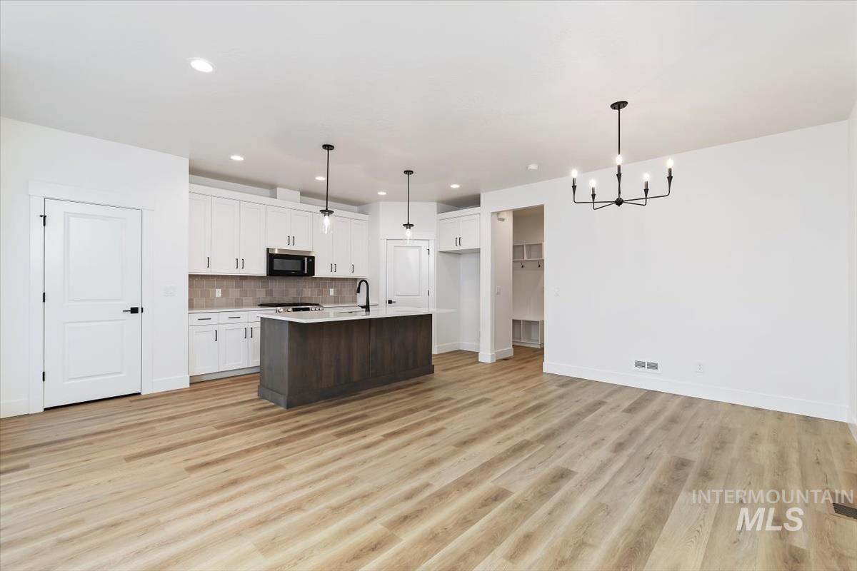 736 South Calhoun Lane Star, ID 83669 - Photo 42 of 42 Kitchen with dual tone cabinetry, a kitchen island with sink, open floor plan, light wood-style flooring, and stainless steel microwave