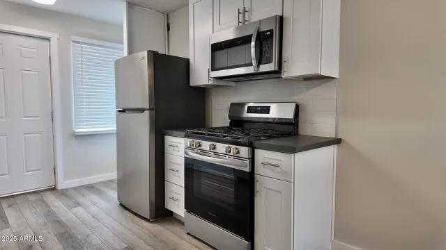 a kitchen with stainless steel appliances granite countertop a stove microwave and refrigerator