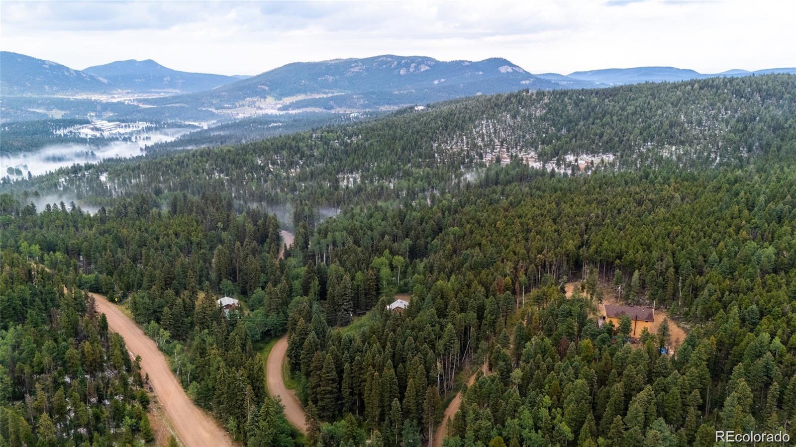 11173 Barney Gulch Road Conifer, CO 80433 - Photo 15 of 16 a view of a lush green hillside and a houses