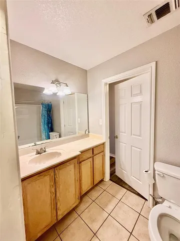 a spacious bathroom with a granite countertop sink a toilet mirror and a