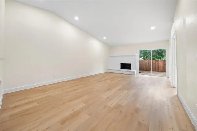 an empty room with wooden floor and a fireplace