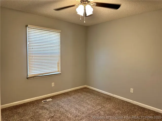 an empty room with a chandelier fan and windows
