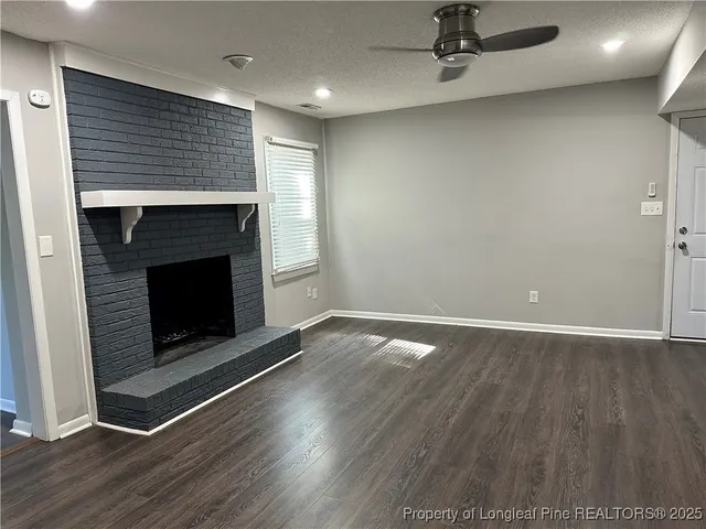 an empty room with wooden floor fireplace and windows
