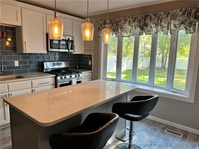 a kitchen with a sink a stove and chairs