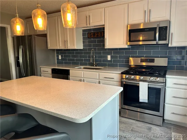 a kitchen with stainless steel appliances a stove a microwave and sink