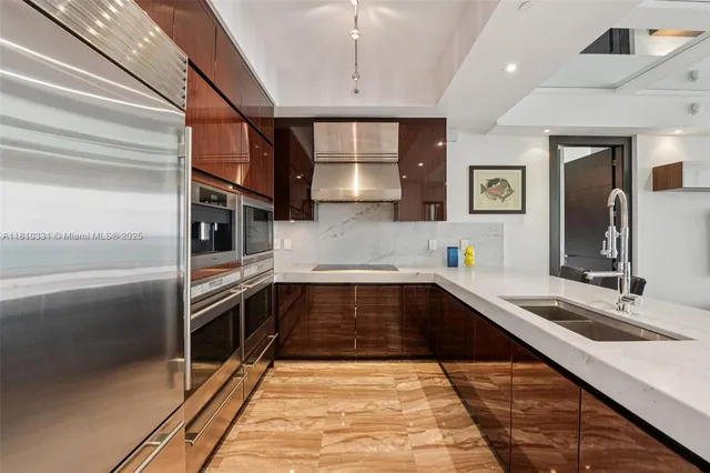 a kitchen with stainless steel appliances kitchen island granite countertop a refrigerator and a sink