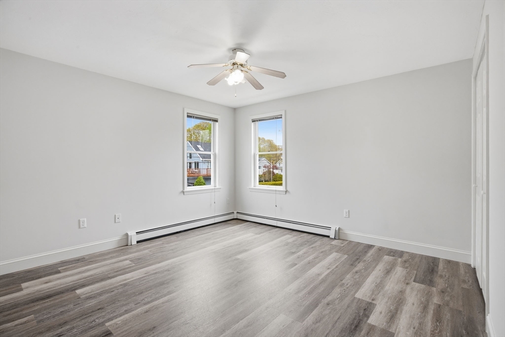 192 Swifts Beach Road Wareham, MA 02571 - Photo 29 of 38 an empty room with wooden floor chandelier fan and windows