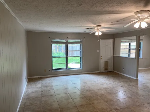 an empty room with chandelier fan and windows