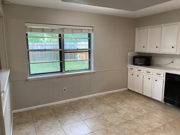 a kitchen with a refrigerator a sink dishwasher and a stove top oven with white cabinets