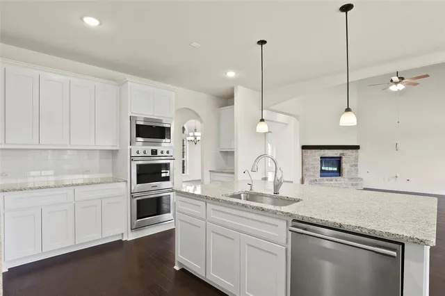 a kitchen with stainless steel appliances granite countertop a sink a stove a microwave a center island and cabinets