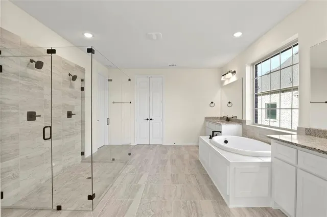a large white bathroom with a bathtub a double vanity sink and mirror