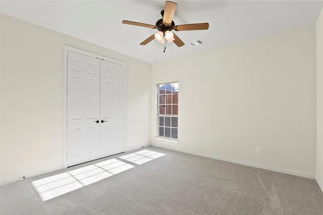 an empty room with a chandelier fan and a ceiling fan