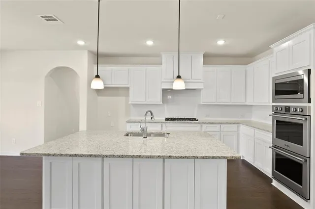 a kitchen with kitchen island granite countertop a sink a counter space appliances and cabinets