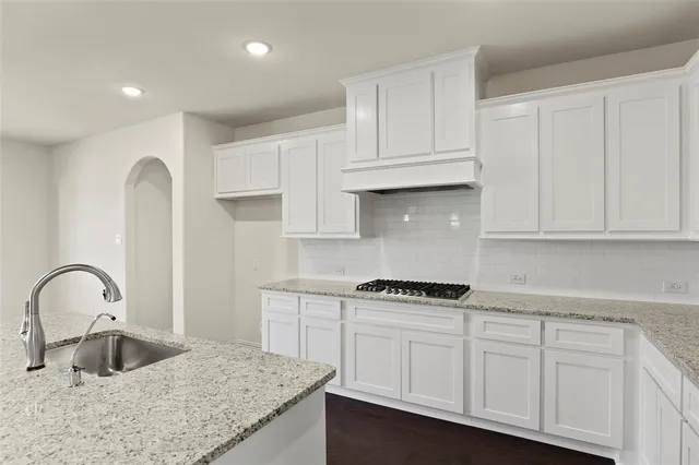 a kitchen with granite countertop white cabinets and sink