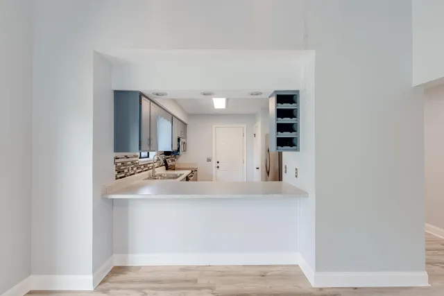 a view of a kitchen with kitchen island a sink wooden floor and living room view
