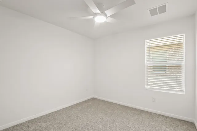 an empty room with a window and a fan