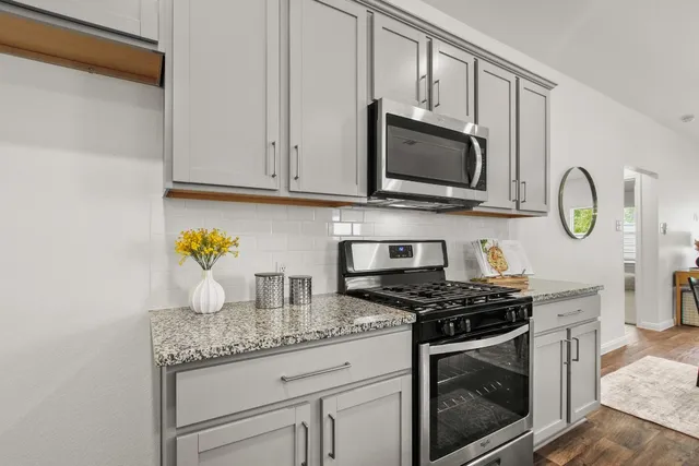 a kitchen with granite countertop a stove sink and microwave