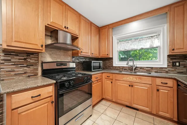 a kitchen with granite countertop white cabinets stainless steel appliances a sink and a window