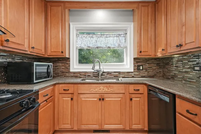a kitchen with granite countertop cabinets stainless steel appliances a sink and window