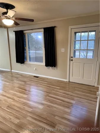 a view of an empty room with wooden floor and windows
