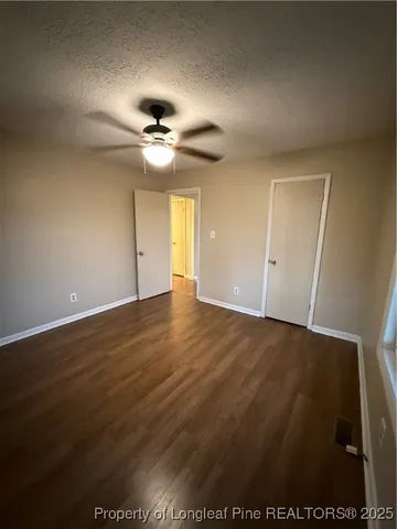 an empty room with wooden floor and fan
