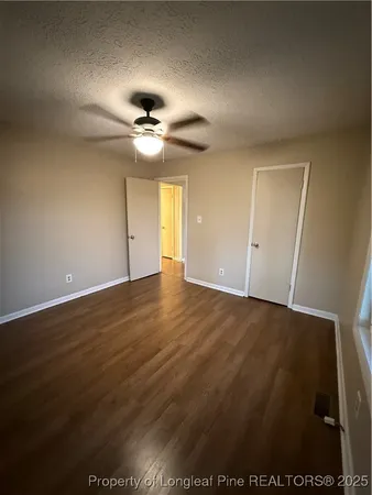 an empty room with wooden floor and fan