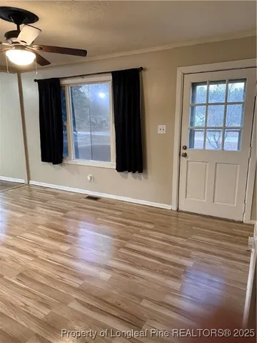 a view of an empty room with wooden floor and a window