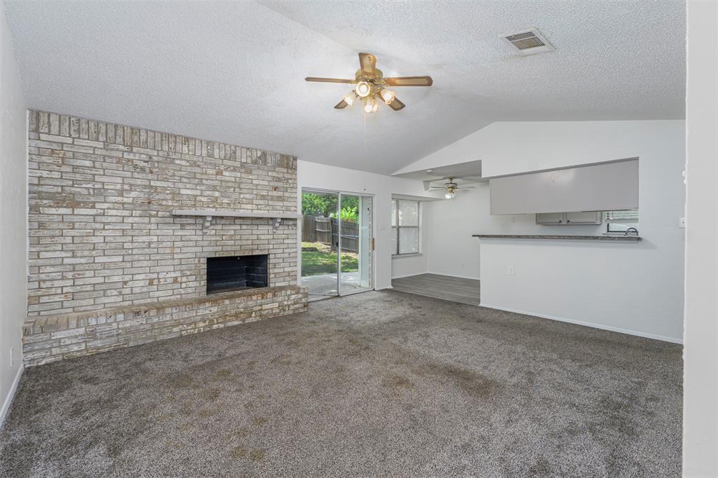 617 Rolling Ridge Court Azle, TX 76020 - Photo 3 of 20 Living area featuring a textured brick fireplace, vaulted ceiling, and carpet flooring