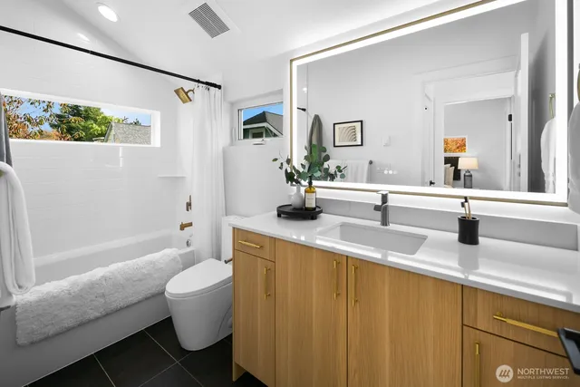 a bathroom with a granite countertop sink a toilet a mirror a vanity and bathtub
