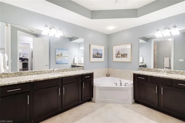 a bathroom with a granite countertop double vanity sink and a bathtub
