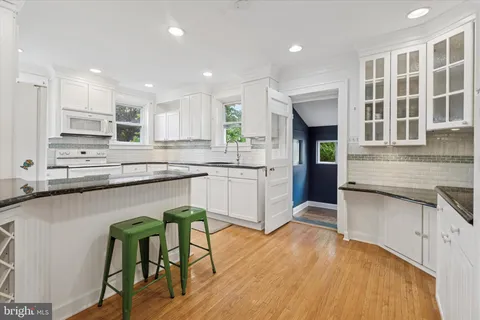 a kitchen with stainless steel appliances granite countertop wooden cabinets a sink a stove a dining table and chairs