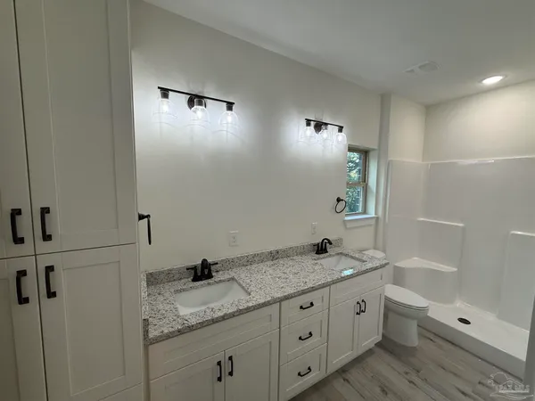 a bathroom with a granite countertop sink a toilet and shower