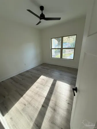 a view of empty room with wooden floor and fan